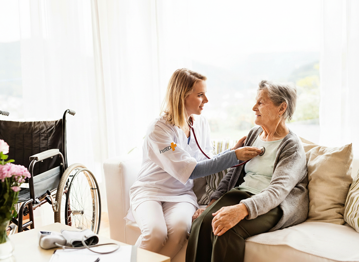 insted worker taking elderly womans vitals checking heartbeat at her home on the couch